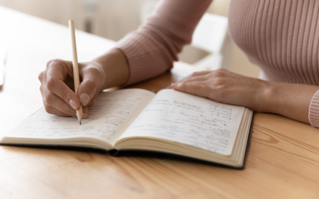 Femme qui écrit à la main dans un carnet